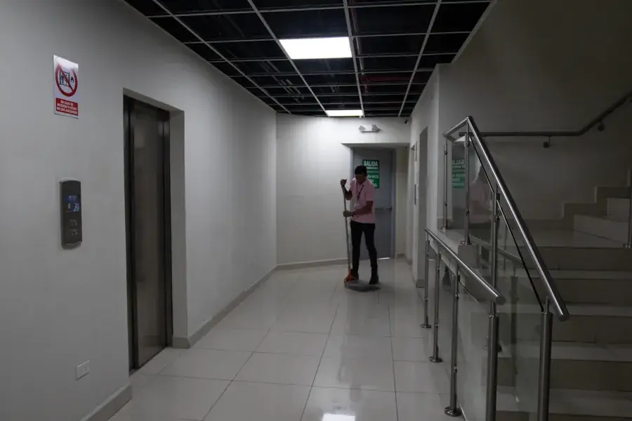 Colaborador de LIMPSA trapeando el pasillo de elevadores de un edificio
