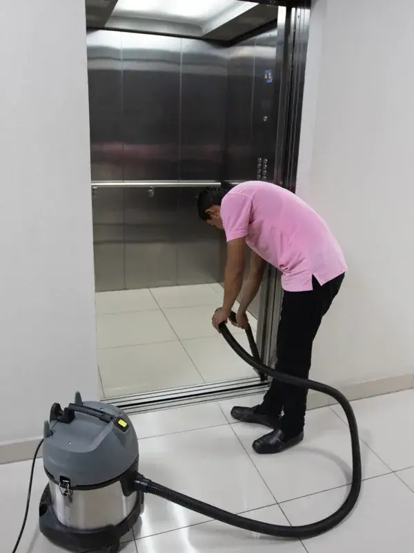 Limpieza de edificios: colaborador de LIMPSA aspirando el piso de un elevador