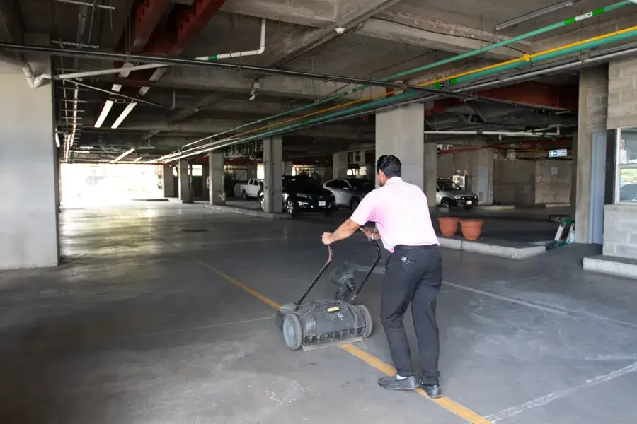 Colaborador de LIMPSA usando una barredora mecánica en un parqueo techado